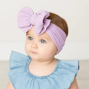Close-up of a baby wearing a large purple floral nylon headband with an elastic bow