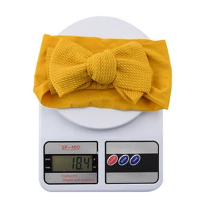 Close-up showing a yellow bow headband on an electronic scale weighing 18.4 grams