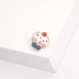 Detail shot of a cute pink cupcake enamel brooch pin on a clean white background