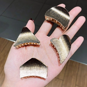 Set of four geometric gold metal hair clips including heart and triangle shapes