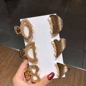 Detailed view of six gold mini geometric hair clips with textured metallic finish