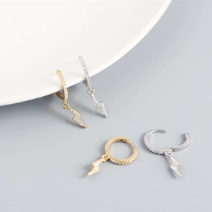 Close-up of gold and silver geometric lightning bolt earrings with pavé crystals