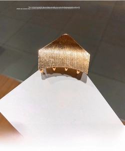 Close-up of golden geometric hair claw clip with vertical striped metallic texture