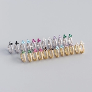 Detailed macro shot of twisted metal hoop earrings with colorful clover zircon stones