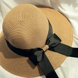 Close-up of the intricate spiral woven straw texture and elegant black grosgrain ribbon bow