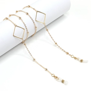 Elegant gold geometric glasses chain with triangle charms and metal beads on a white pedestal