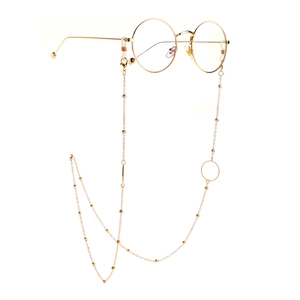 Detail of round gold glasses frame with matching beaded decorative eyewear chain