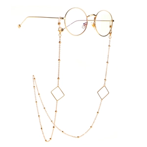 Detailed shot of golden round glasses featuring geometric triangle chain accessories