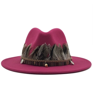 Close-up of rose red fedora with feather trim, woven bands and metallic charms