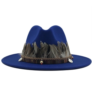 Close-up of royal blue wool fedora hat featuring gray feather trim and ethnic beaded band