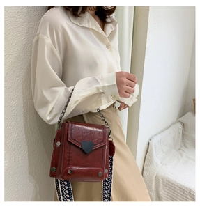 Detailansicht der rotbraunen PU-Ledertasche mit schwarzem Herzverschluss und Riemen