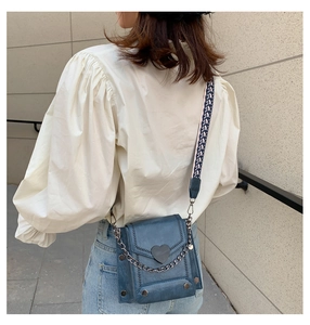 Blaue Denim Umhängetasche mit Herz-Detail und Kettenriemen getragen von Modell