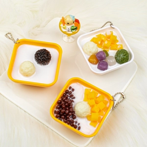 Close-up of realistic PVC dessert charms with mango and taro ball toppings on white fur