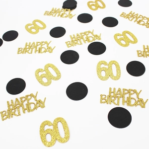 Macro shot of gold glitter 60th birthday confetti and black sequins on white background