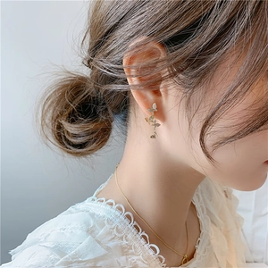Elegant gold butterfly drop earrings with shimmering accents worn on a female model