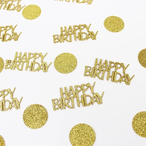 Close-up of golden glitter Happy Birthday confetti and round sequins for party table decor