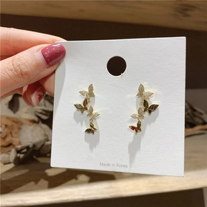 Detail view of small golden butterfly stud earrings with sparkling zircon inlay on white card