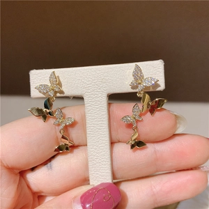 Macro shot of tiered golden butterfly earrings with sparkling white zircon stones