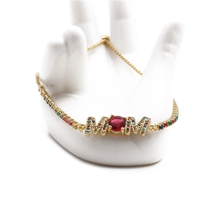Adjustable gold MOM bracelet with colorful zircons and red center stone on ceramic hand