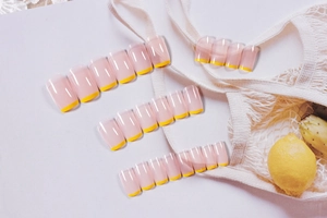 Macro view of French nude press-on nails with bright yellow square tips and 24 pieces
