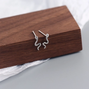 S925 sterling silver snake stud earrings with crystal stones on a wooden block