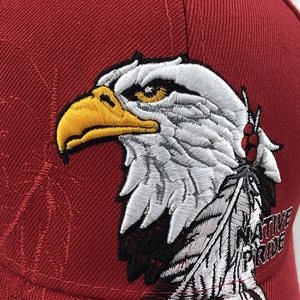 Close-up of red baseball cap featuring detailed eagle head and Native Pride embroidery