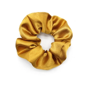 Close-up of golden satin scrunchie showing smooth texture and glossy fabric finish