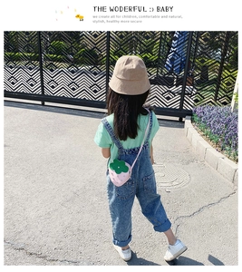Pink strawberry crossbody bag shown on child model wearing casual denim overalls set