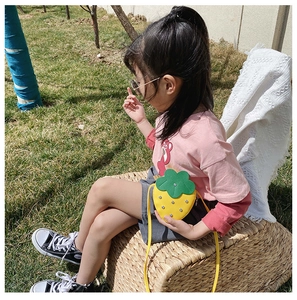 Close-up of yellow strawberry shape crossbody bag for kids with silver studs and green leaf