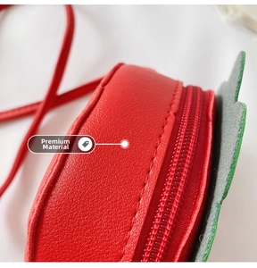 Close-up of red strawberry purse showing lychee texture leather and green leaf detail