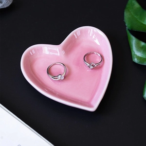 Pink heart-shaped ceramic jewelry dish for rings and snacks on a black desk