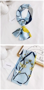 Detail view of light blue silk scarf with yellow floral pattern on satin fabric