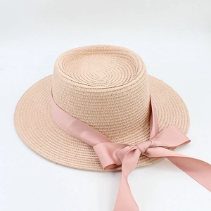Detailed close-up of woven straw sun hat texture with elegant pink satin ribbon bow