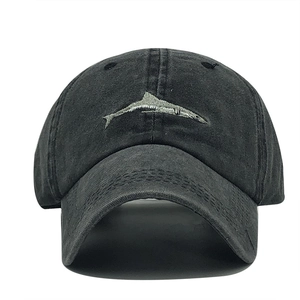 Close-up of a silver fish embroidery on a washed black cotton baseball cap surface