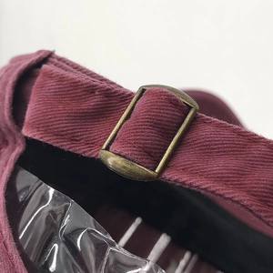 Detail shot of the maroon cotton baseball cap showing the bronze metal adjustable buckle