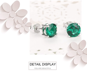 Détail macro de boucles d'oreilles émeraude en argent 925 avec serti à quatre griffes