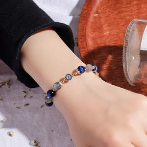 Blue moonstone and evil eye beaded bracelet on woman's wrist with natural wooden decor