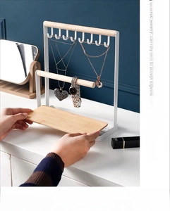 Close-up of white iron jewelry rack with six hooks and wooden base for necklace storage