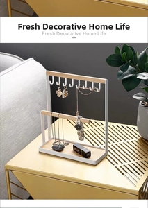 Detail of white iron jewelry rack with wooden base for organizing necklaces and watches
