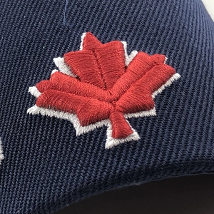 Close-up of high-density 3D embroidered red maple leaf on navy twill baseball cap