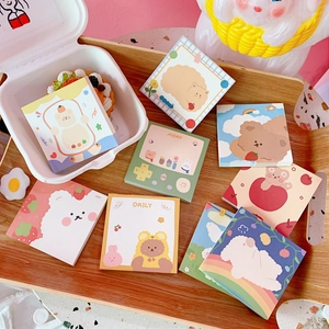 Flat lay of cute cartoon bear memo pads and sticky notes on a wooden tray