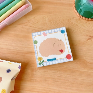 Flat lay of a cute cartoon cat memo pad on a wooden desk with creative stationery