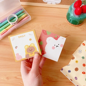 Close-up of cute cartoon bear and strawberry sticky notes on a wooden desk setup