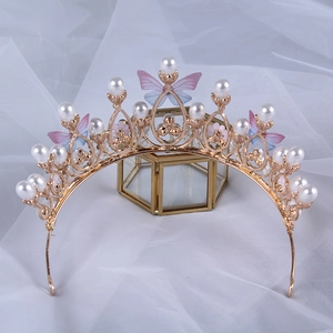 Detail of golden crown with white pearls and blue butterflies on soft white tulle