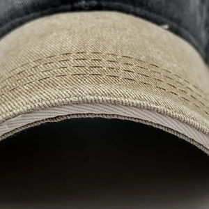 Detailed close-up of khaki cotton brim with precision stitching on a baseball cap