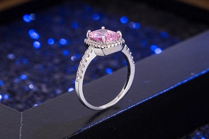 Detail of silver square pink zircon ring with halo diamonds on dark bokeh background