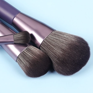 Close-up of two makeup brushes with purple metallic handles and soft synthetic bristles