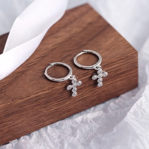 Detail of S925 sterling silver mini cross hoop earrings with sparkling stones on wood