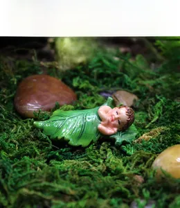 Macro detail of fairy baby sleeping in green resin leaf for succulent garden decor
