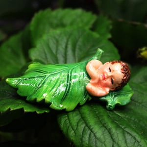 Garden figurine of a sleeping baby in green leaves for micro landscape decor